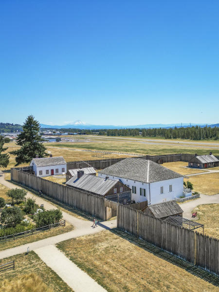 Overhead view of the historic buildings and fencing of Fort Vancouver National Historic Site with blue sky and Mount Hood in the background
