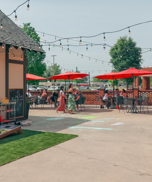 Outside Straight to Ale at Campus 805 with red umbrellas shading outdoor dining on a sunny day