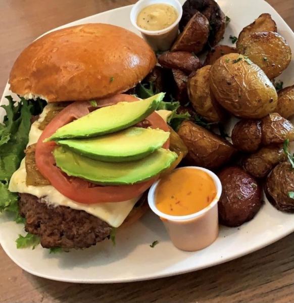 burger dish served with a side of roasted potatoes and sauce