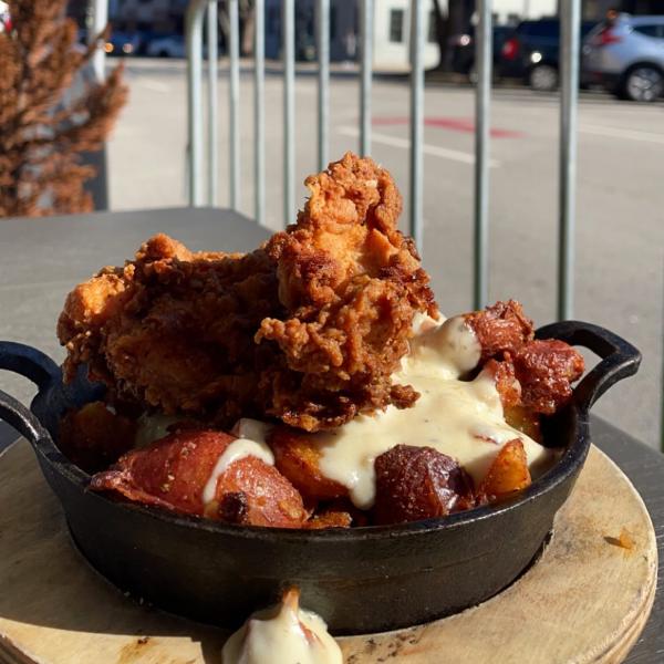 A piece of fried chicken and potatoes on a black skillet