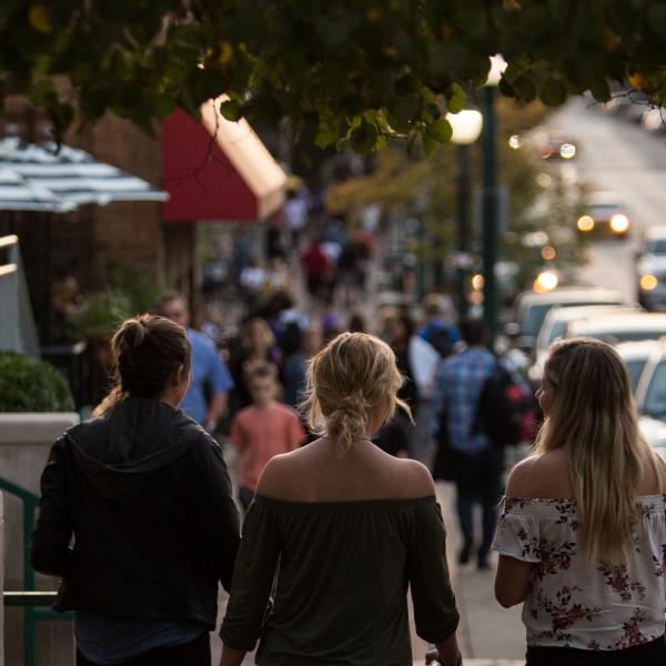 Three women walking down Kirkwood Avenue on a fall evening