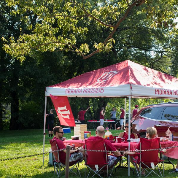 People tailgating under a canopy