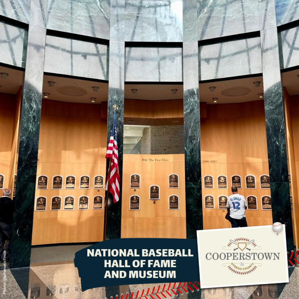 An image of the baseball hall of fame plaque gallery, with 25 plaques on light brown walls, an american flag, and a banner below that says National baseball hall of fame and museum.