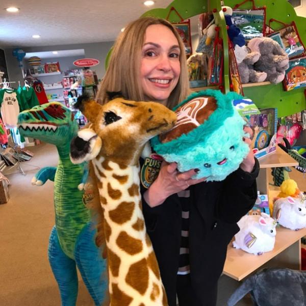 Owner of Dublin Toy Emporium holding stuffed animals smiling at camera.