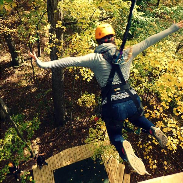 Woman ziplining during fall foliage.