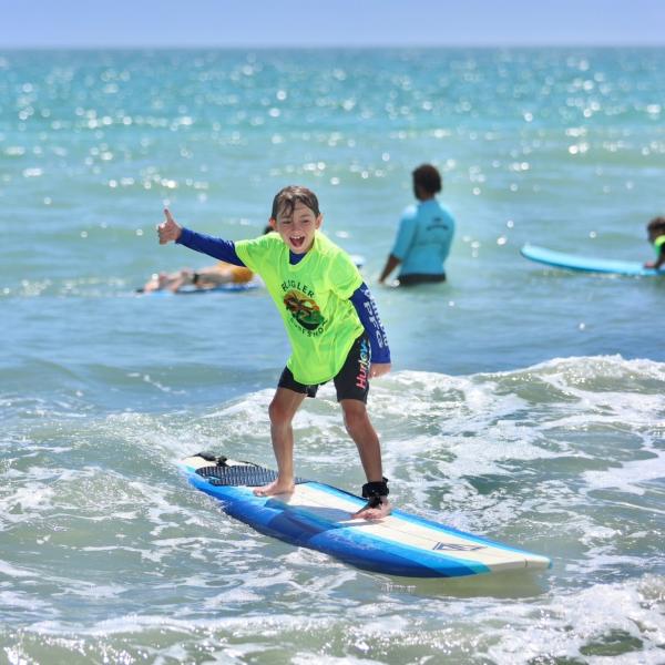 A child rides a surfboard during a Flagler Surf School summer camp in Flagler Beach, Florida.