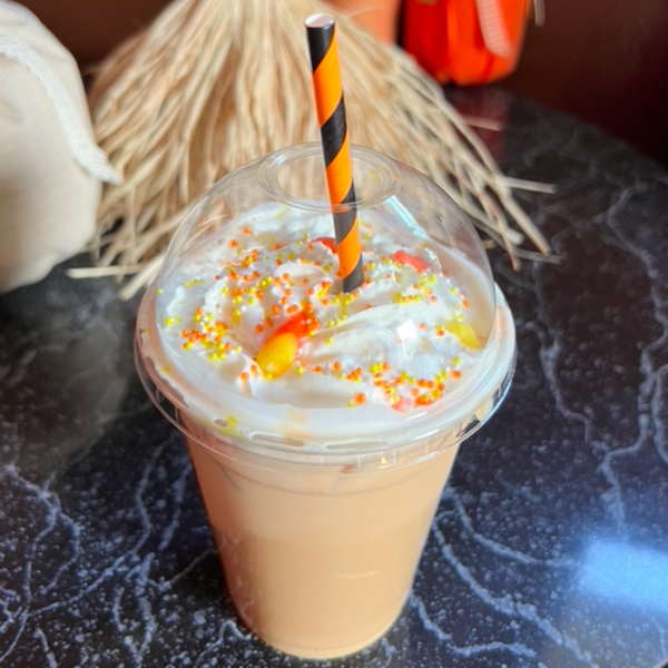 coffee beverage in a to go cup with a black and orange striped straw