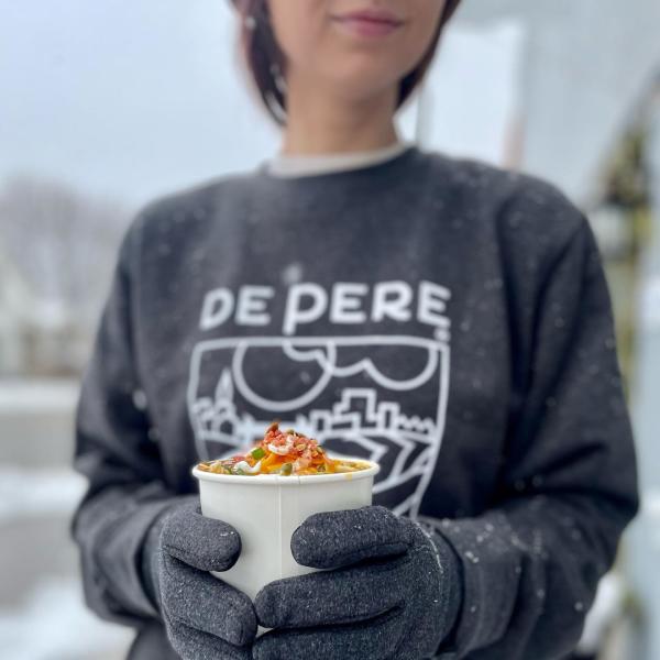 Girl holding a cup of soup wearing a de pere sweater