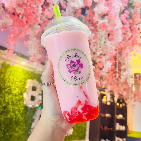 Photo of hand holding boba bae pink drink