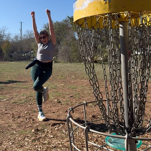 A woman celebrates landing the throw at Flying Armadillo Disc Golf Club in San Marcos, Texas