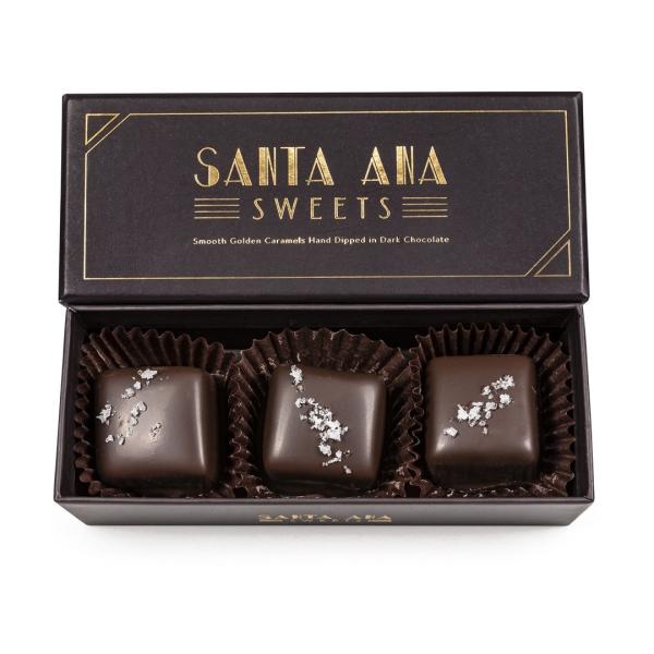 Elegant box of Santa Ana Sweets featuring three dark chocolate caramels topped with a sprinkle of sea salt, packaged in a sleek black box with gold lettering.