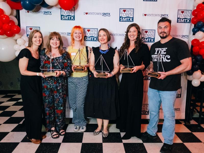Group photo of the love downtown award winners holding their trophies in front of a Downtown SMTX step and repeat