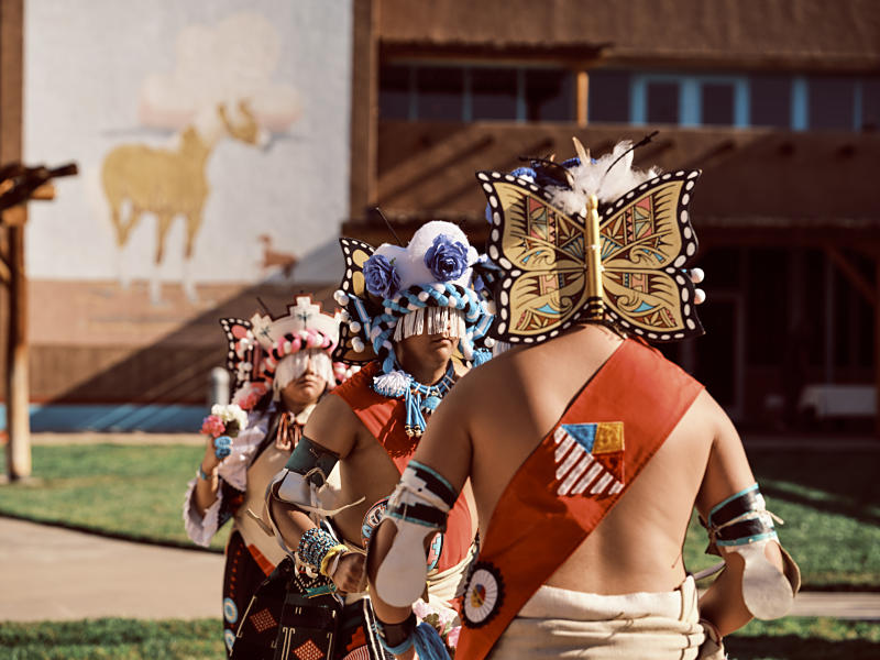 Native dancers face away from the camera while performing at the Indian Pueblo Cultural Center