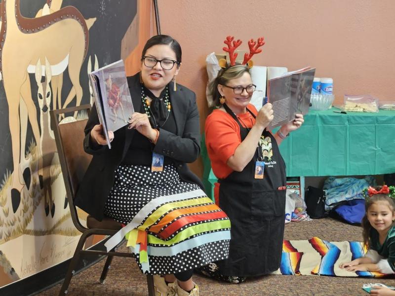Two women read picture books at the Indian Pueblo Cultural Center.