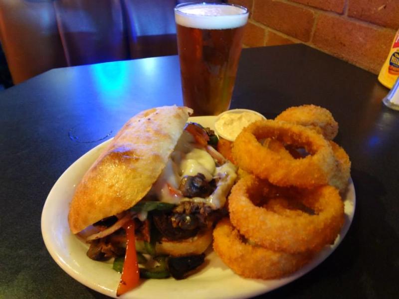 A philly cheese steak, onion rings and glass of beer from Spectators Sports Bar and Grill