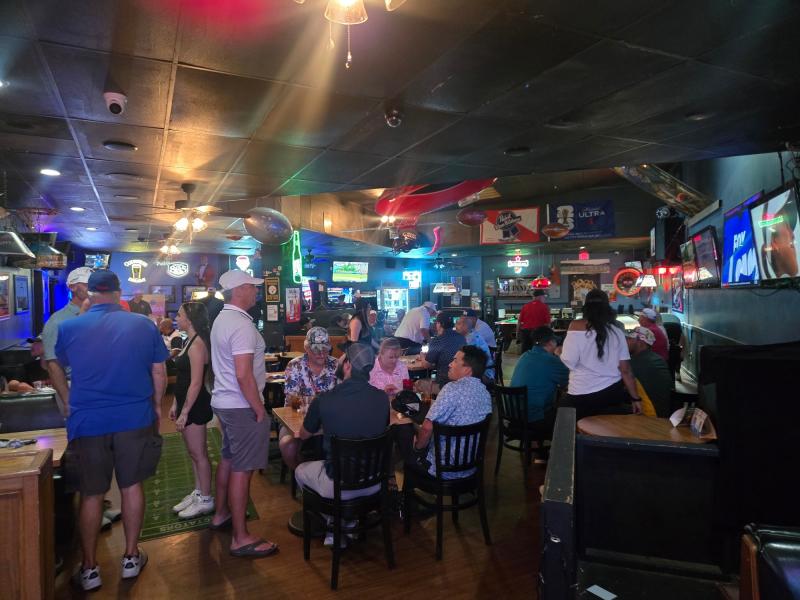 Customers mingle in a dimly lit sports bar, Spectators Sports Bar & Grill.