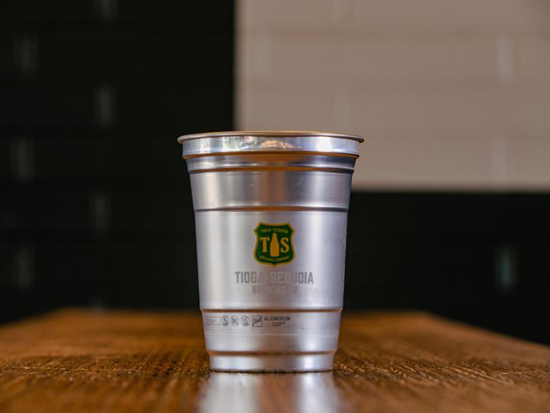 Aluminum glass with Tioga Sequoia logo sits on table.
