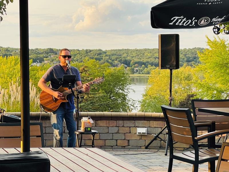 Musician playing guitar on a patio overlooking the lake