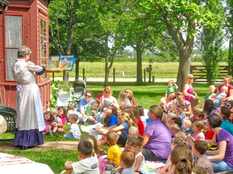 Worker reading picture book to children at Historic Eidem Farm