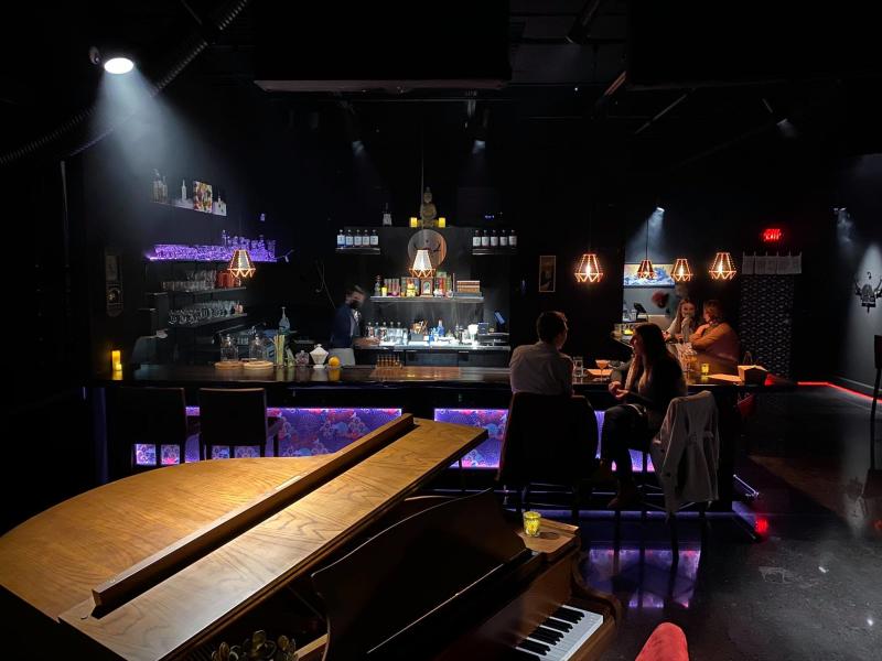 A couple dines along a bar with glowing purple lights at Skaalvenn Distillery cocktail lounge