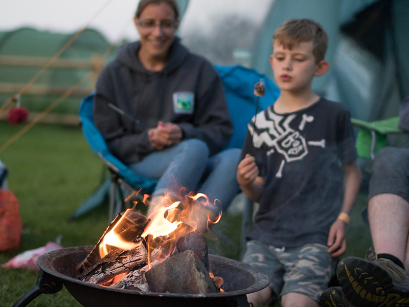 Family marshmallow roasting around a campfire at Harry's Field