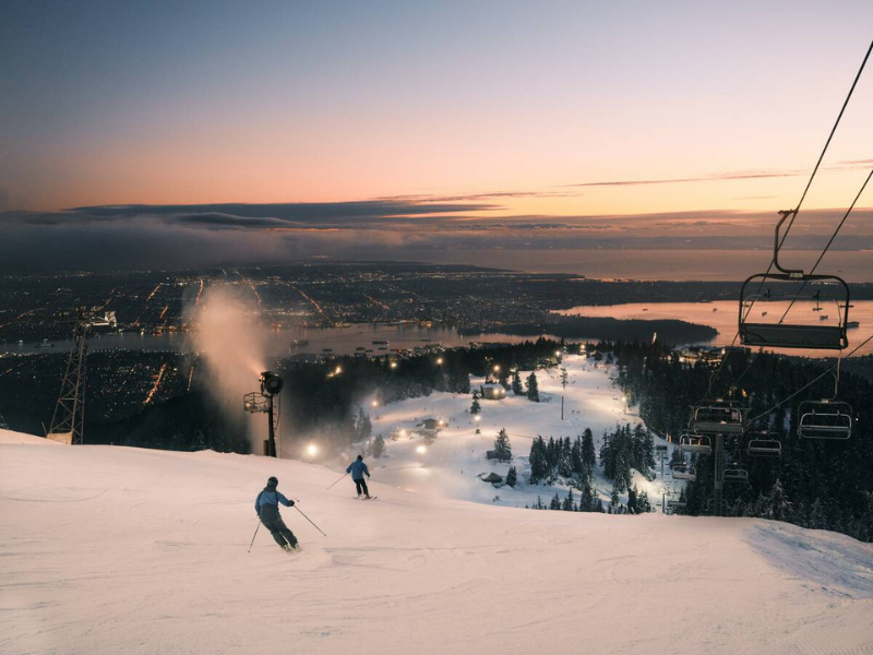 Skiiers at night going down Grouse Mountain