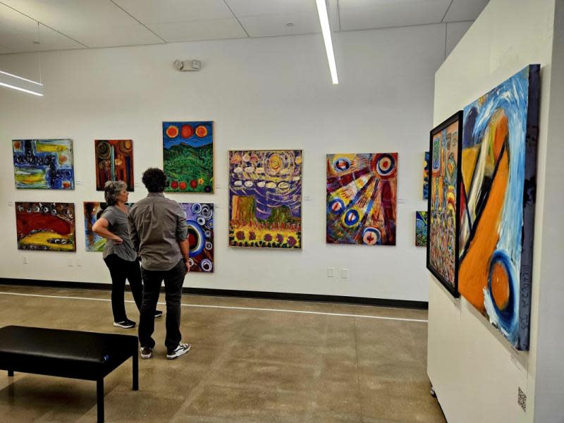 Two people discuss artwork displayed on the walls at Envision Arts Gallery
