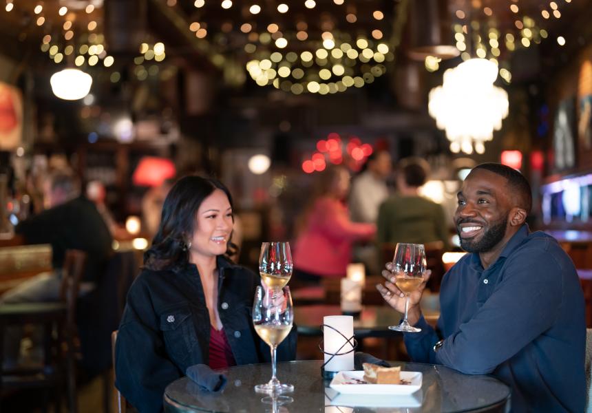 Couple sitting under twinkly lights, drinking wine