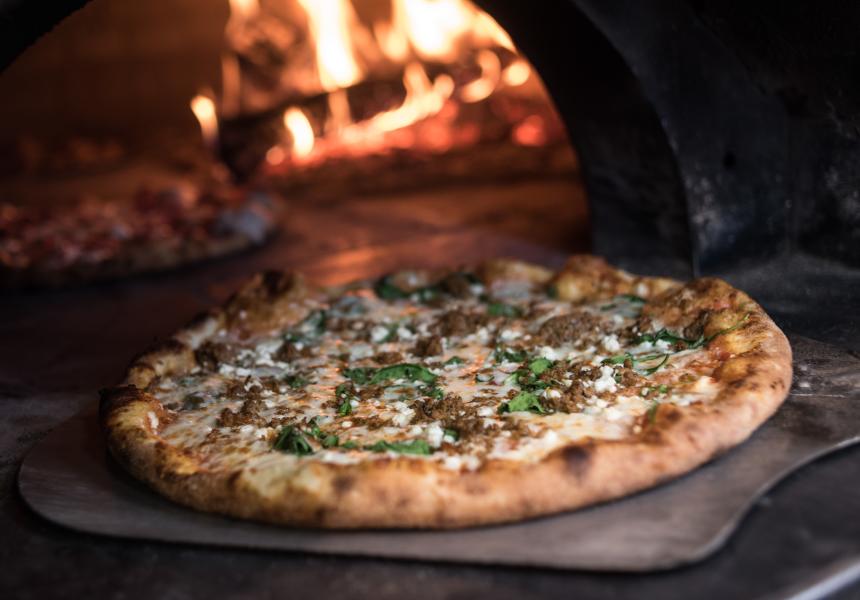 Pizza coming out of wood fire oven