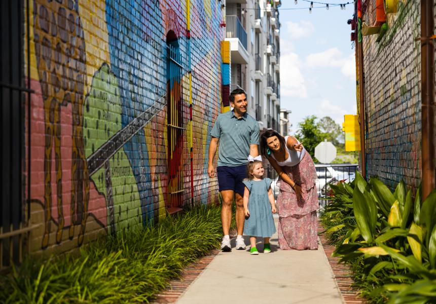 Family of three looks at a brightly colored mural