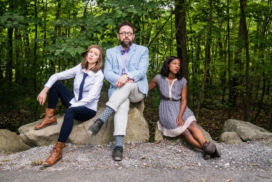 Actors from As You Like It sitting on rock in the woods