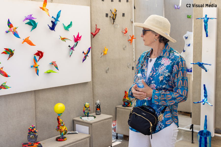 Woman in hat and sunglasses looking at Ann Arbor art booth with folded paper birds