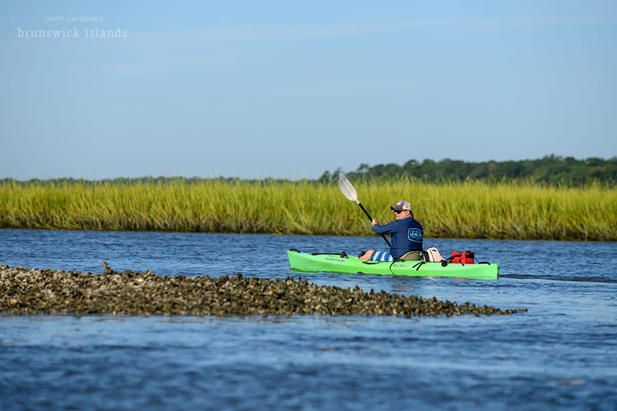 a man kayaking through the marsh around Sunset Beach