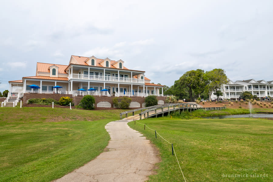 a golf club house with a wooden golf cart bridge - Brick Landing clubhouse