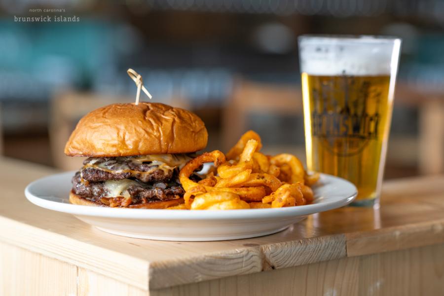 a burger and fries on a plate with a glass of beer