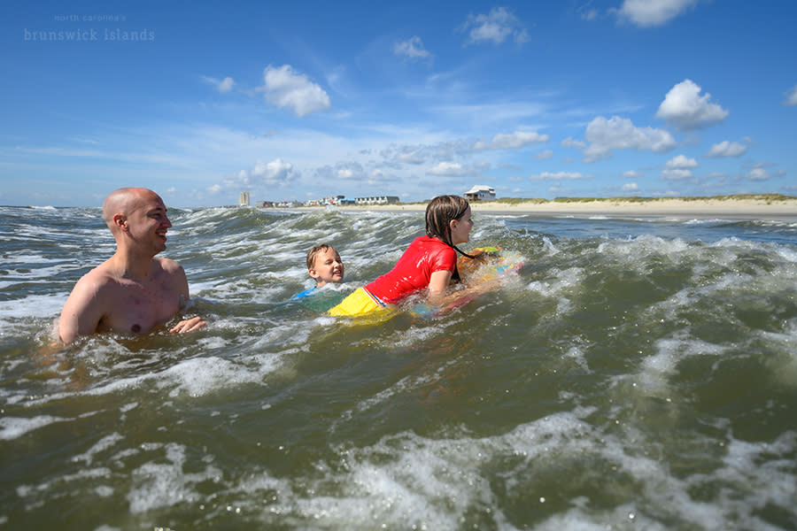a father playing with his kids in the ocean