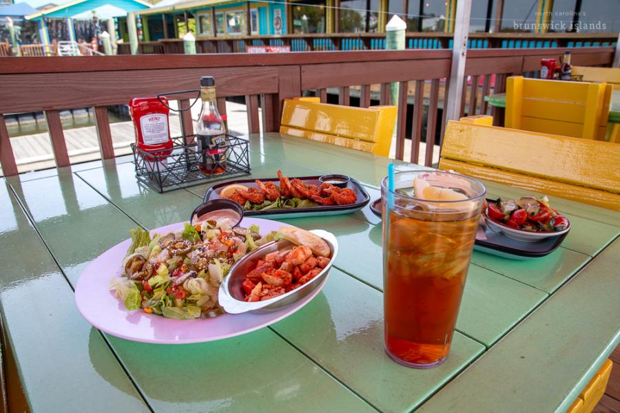 a table of food from Fishy Fishy Cafe including a salad, sweet tea, and coconut shrimp