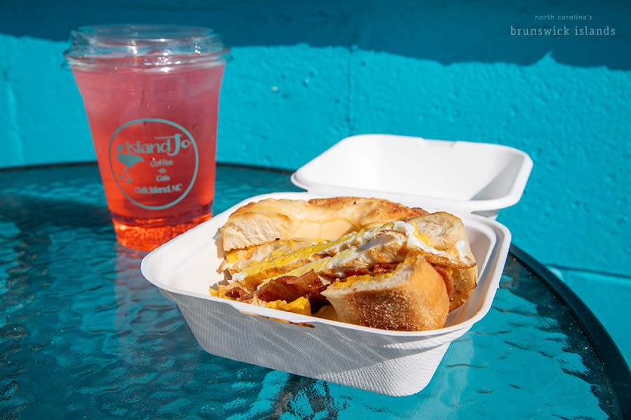a breakfast bagel sandwich and iced bright pink drink from island jo coffee & cafe on Oak Island, NC