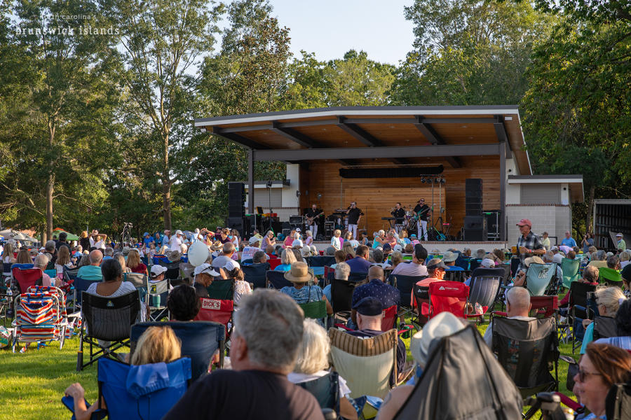 a large group of people watching an outdoor concert in Leland, NC