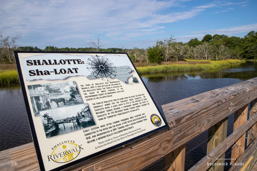 an informational sign along a wooden walkway overlooking a river