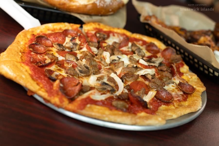a handcrafted pizza with pepperoni, sausage, and onions