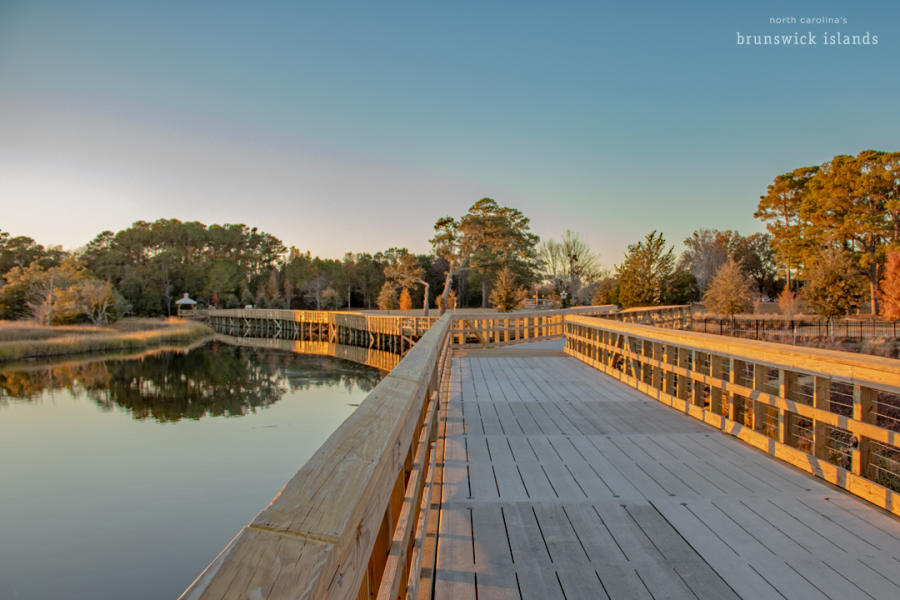 A wooden walkway along a river at sunset