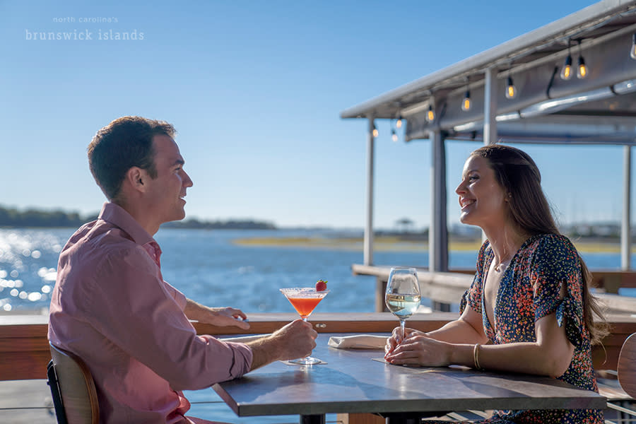 a couple talking over drinks at a waterfront restaurant