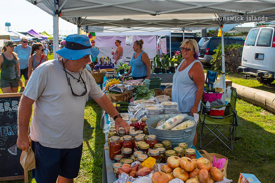 a man buying preserved vegetables at an outdoor market stand on Oak Island