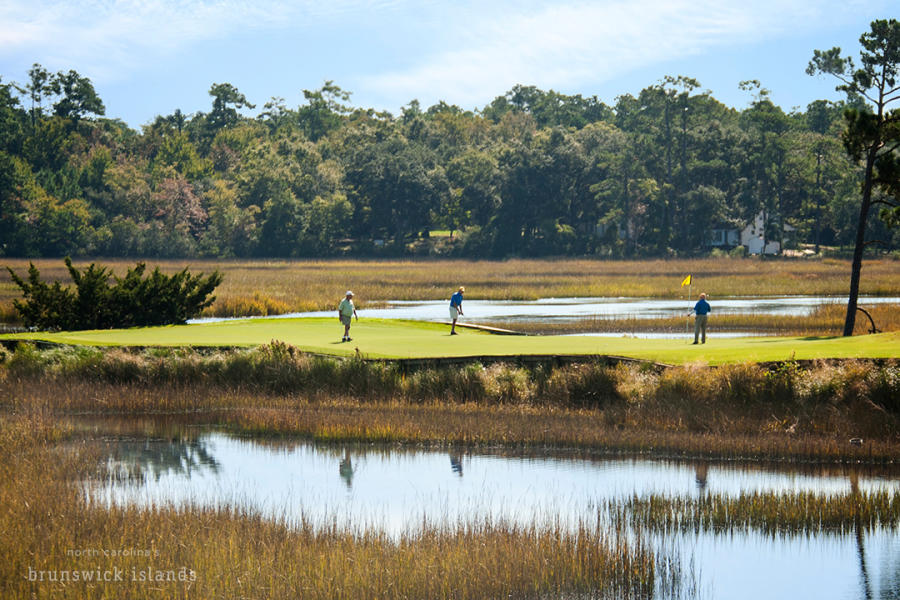 a trio of golfers on a green surrounded by water on River's Edge Golf Course