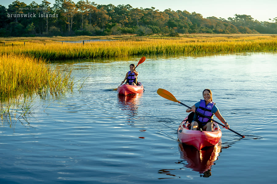 A mother and daughter kayaking through the marsh