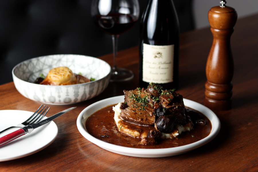 Plated dinner table with steak covered in sauce and mushrooms on top of potatoes.