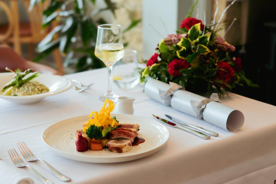 A delicious roast turkey Christmas lunch with a glass of white wine, cracker and Christmas flower arrangment