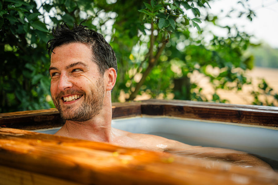A smiling man sitting in an ice bath at Scenic Sauna