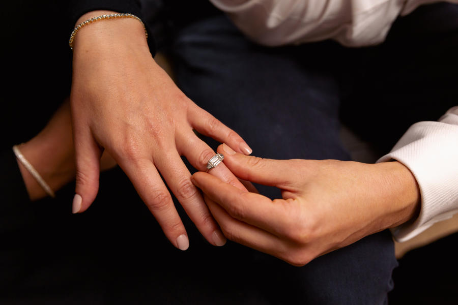 An engagement ring by Walter Bull being slid onto a lady's ring finger